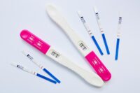 A positive home pregnancy test displaying two lines against a light bathroom background, representing early confirmation of pregnancy.